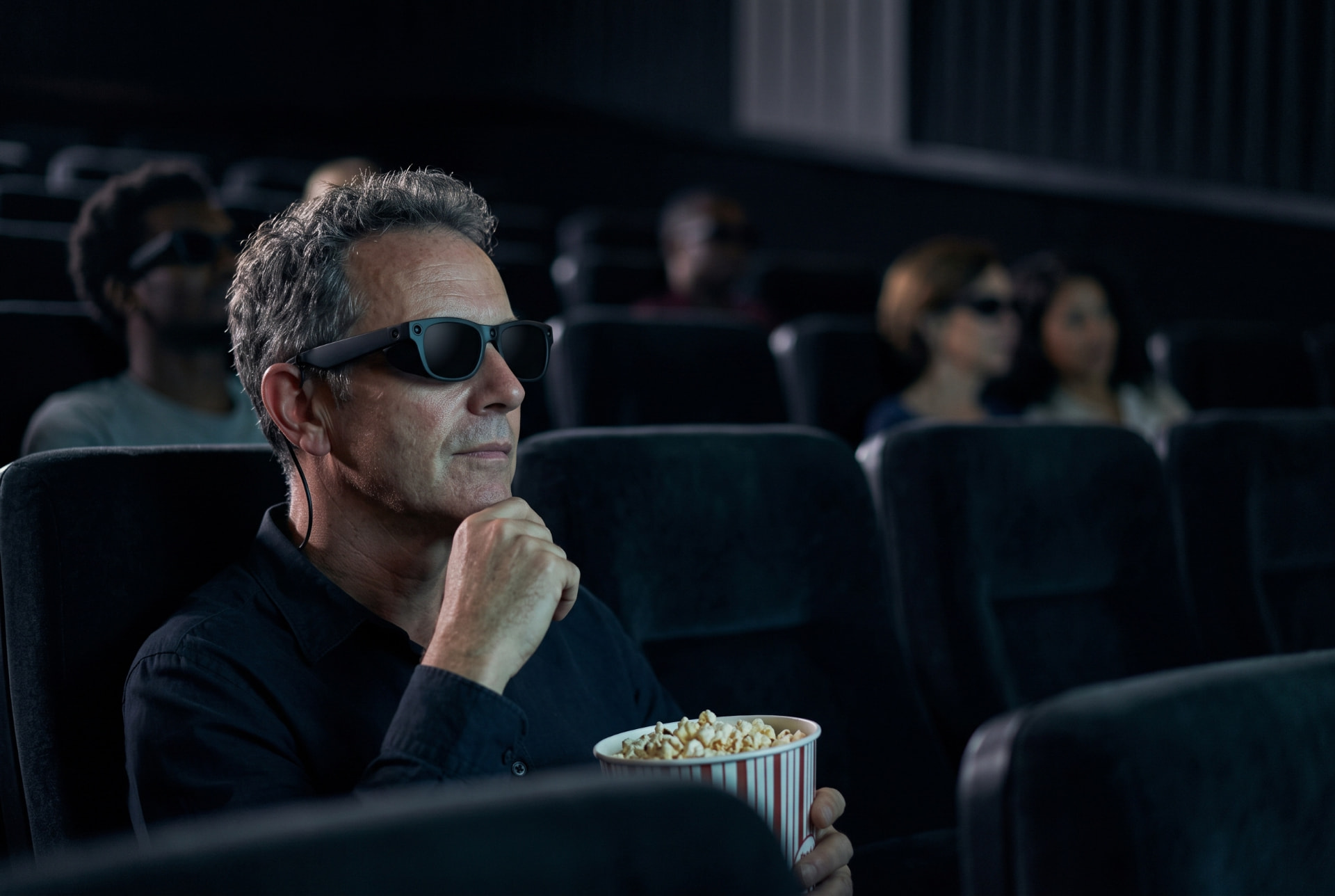 A man watching a film in a cinema, wearing eyesee glasses